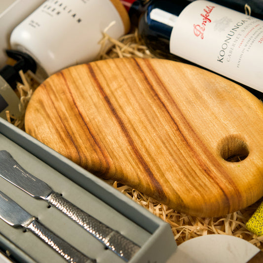 Wooden cutting board with knives and wine bottles in a gift box
